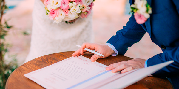 foto com um homem e uma mulher assinando um livro de casamento em cartório